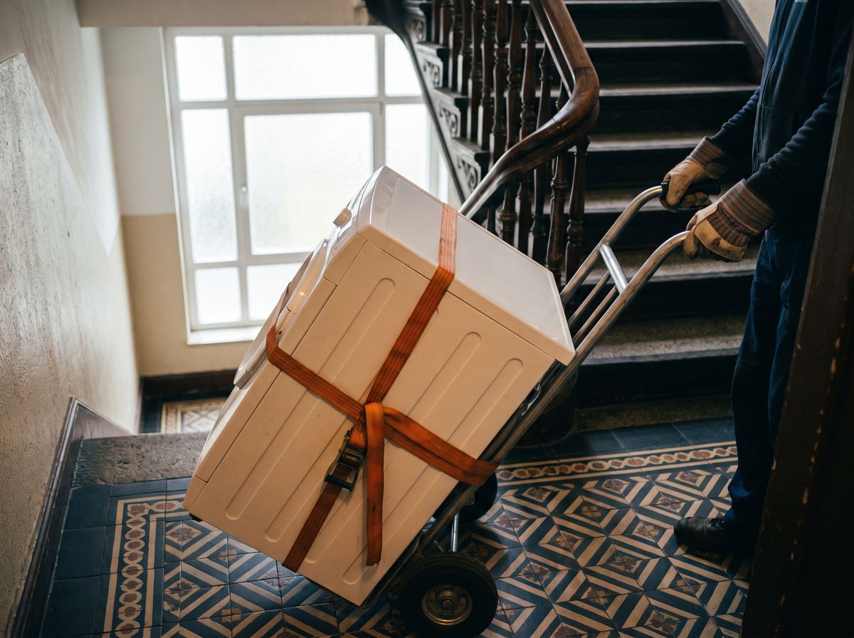 Waschmaschine auf einer Sackkarre im Treppenhaus